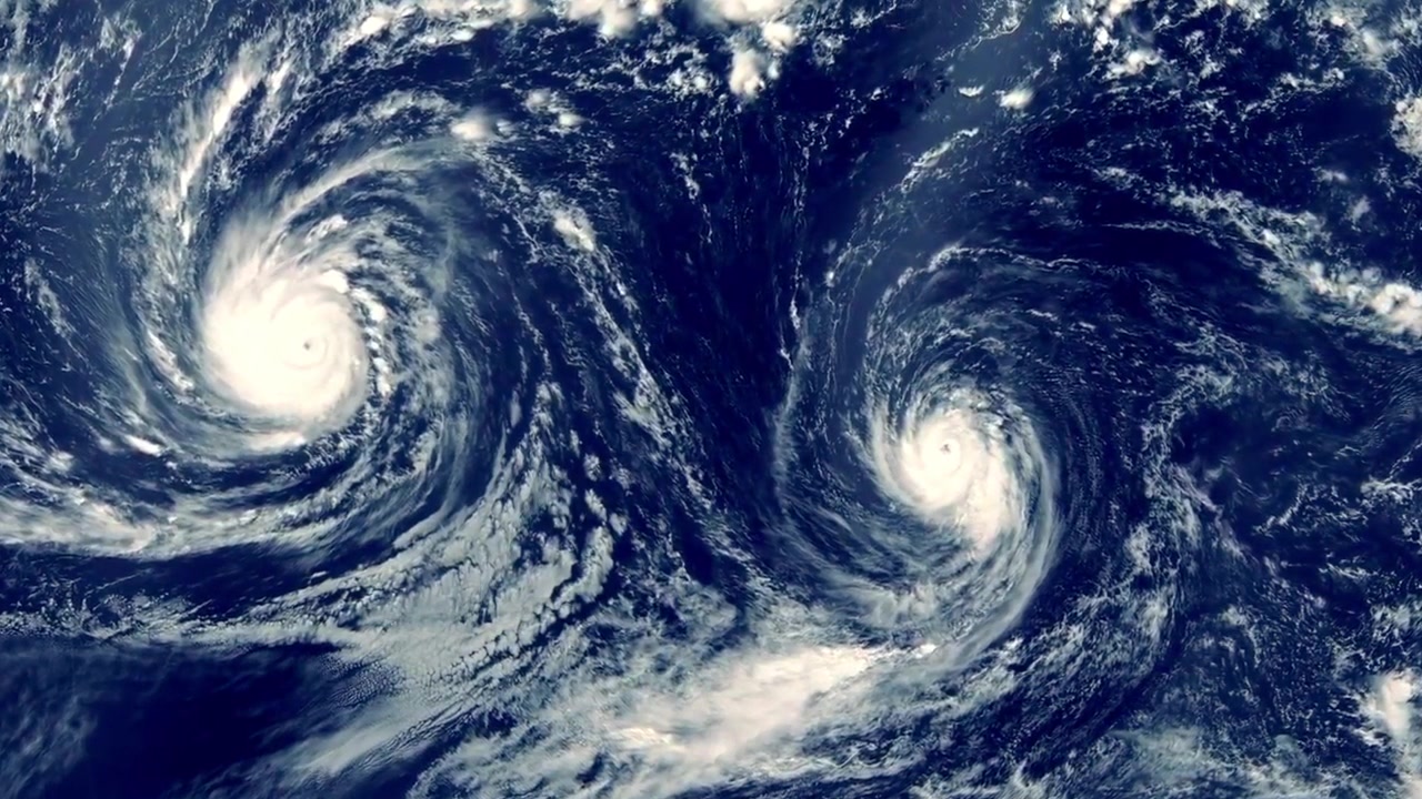 Satellitbillede af to massive orkaner, der hvirvler over havet. Ekstremt vejrsystem med tvillingcykloner, hvide skyhvirvler og dyb havoverflade set fra rummet.