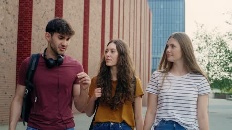 tres estudiantes caucásicos caminando por el campus de la universidad