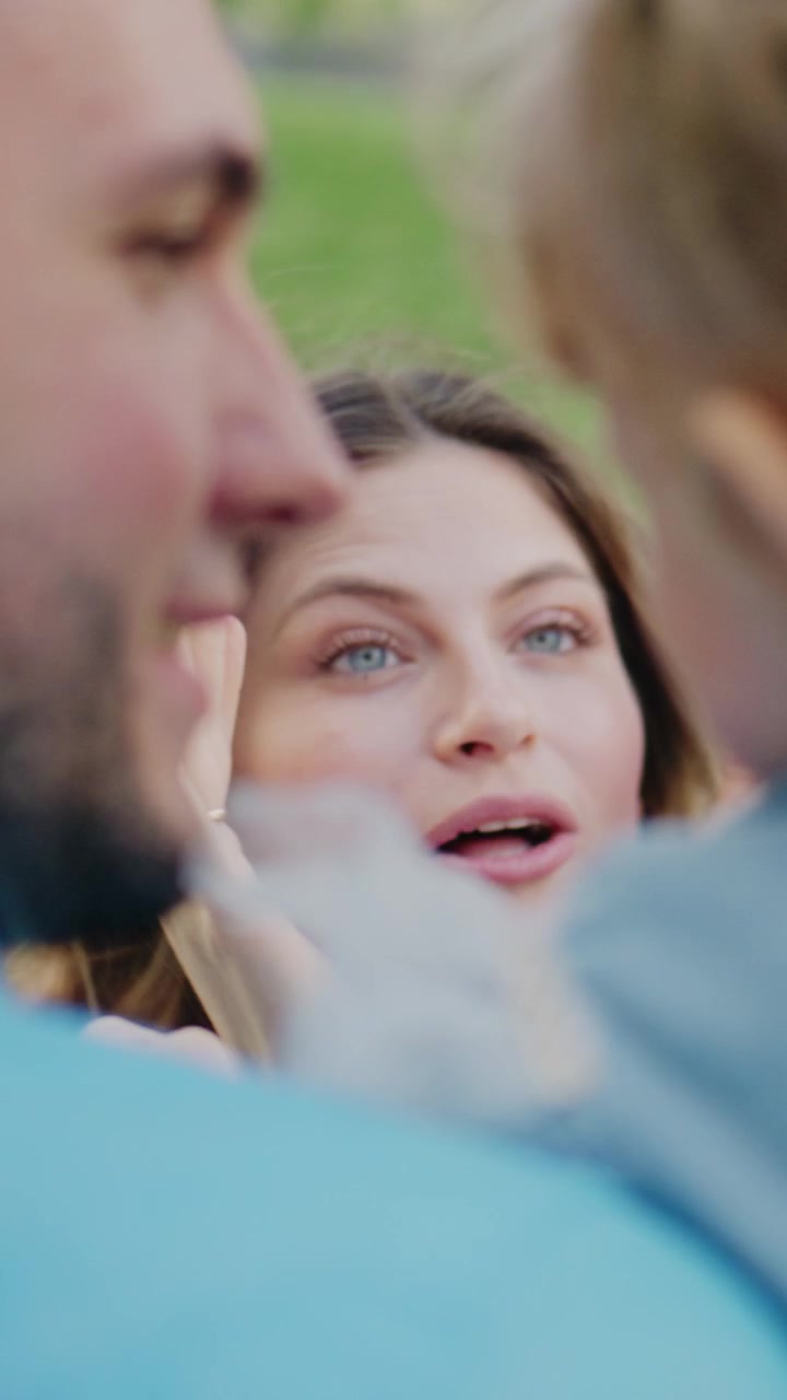 Woman looks surprised as smoke drifts near her face. She smiles playfully as someone blows smoke at her. Young girl with braids hugs a man tightly. The girl leans into him, showing affection