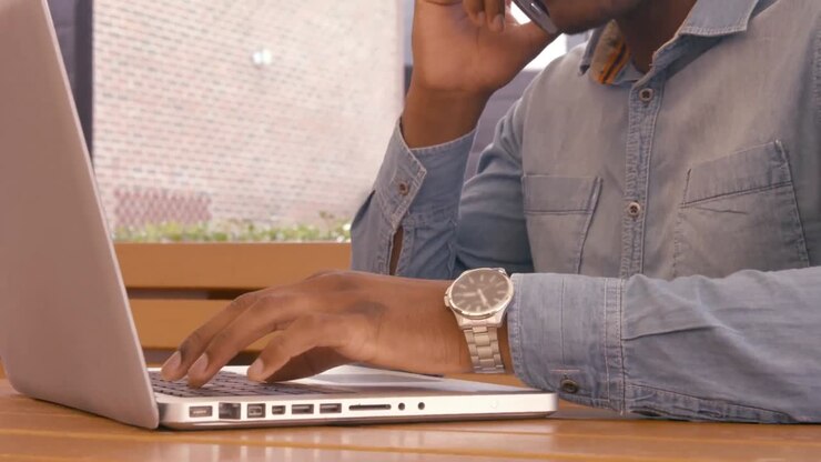 Handsome man using laptop and having phone call