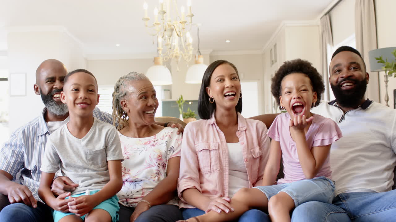 Smiling multi-generational african american family sitting on couch, enjoying time together at home