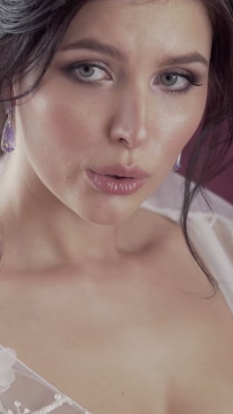 gorgeous brunette bride with exciting hairstyle and brilliant earrings breathes deeply slow motion closeup