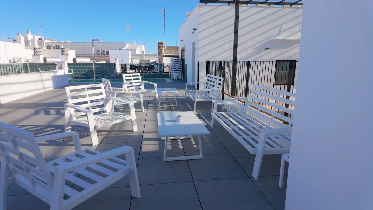 terraza en la azotea con muebles de patio blancos que consisten en sillas y mesas