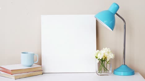 Stack-of-books,-blank-board,-flower-vase,-cup-of-tea-and-table-lamp