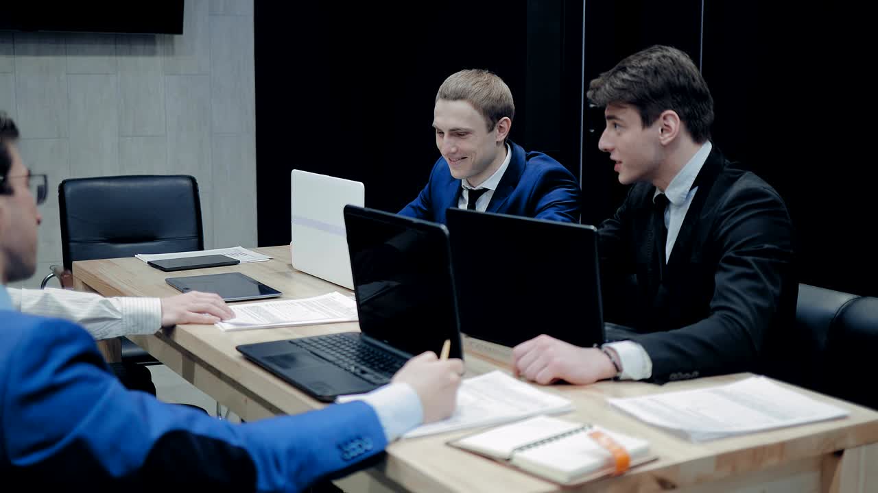коллеги проводят совещание, обсуждают планы компании. мужчины жестикулируют и улыбаются.