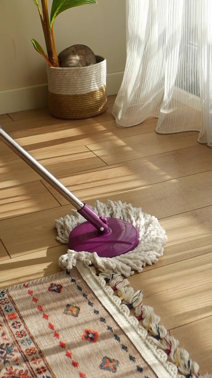 Person mopper tregulv i solfylt stue