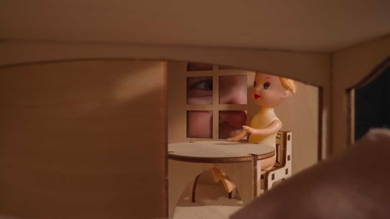 작은 아이의 파란 눈이 인형집의 창문을 통해 들여다본다.