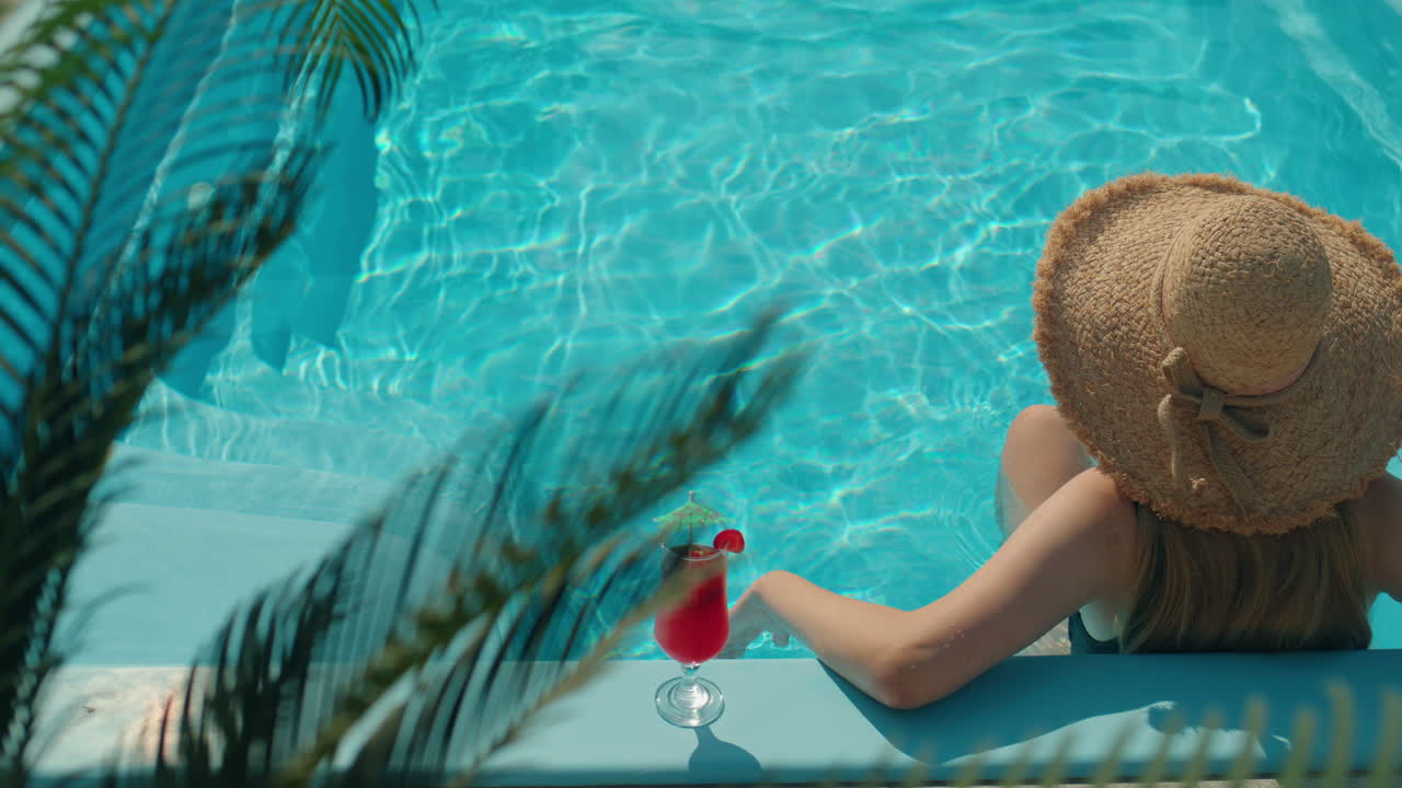 Frau entspannt im Pool mit einem Cocktail