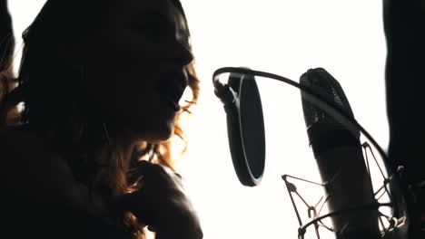young woman recording a song in a professional recording studio. female vocal. black and white.