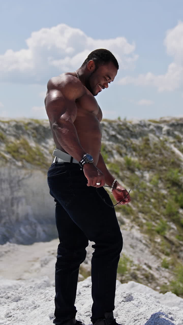 Full length view of the muscular handsome man with naked torso outdoor. Athletic naked man standing outside and looking at the views. Vertical video