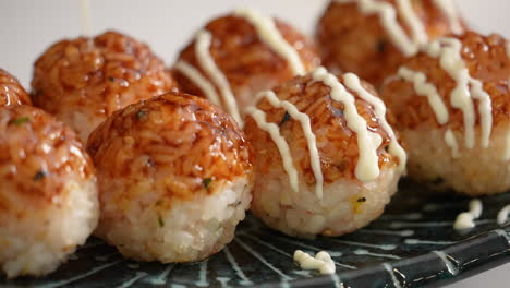 süße soja-yaki-sauce und mayonnaise auf kleinen runden reiskugeln im takoyaki-stil zu hause bürsten