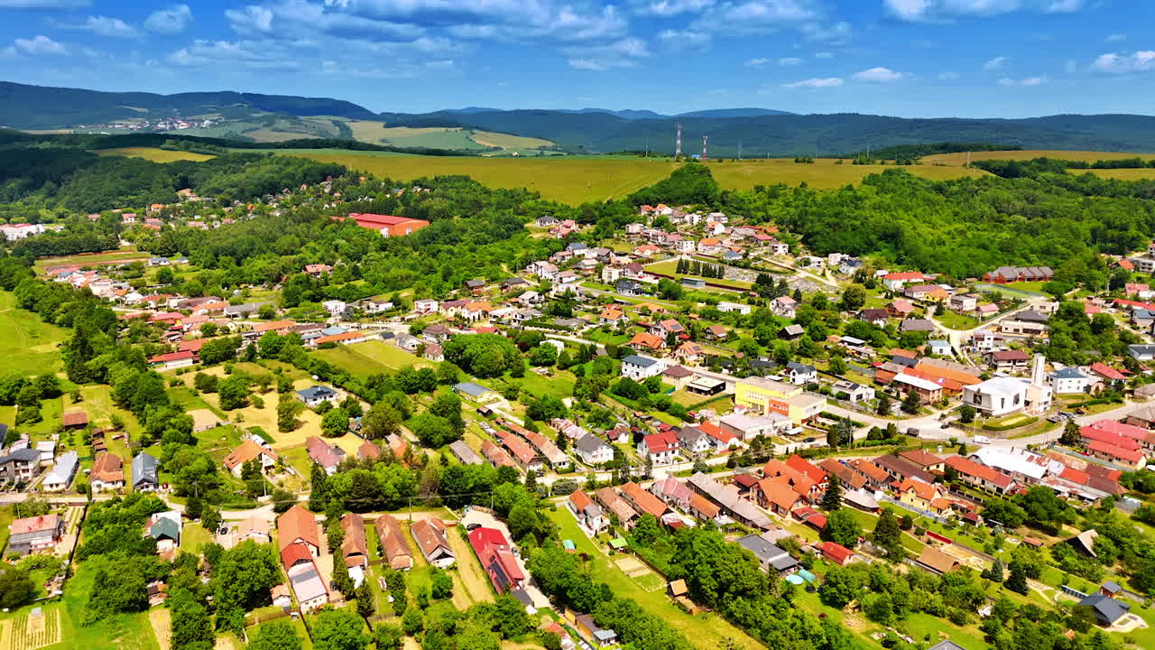 Sunny European village scene. Aerial view of a picturesque village surrounded by lush greenery and rolling hills under a clear blue sky