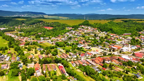 sunny european village scene. aerial view of a picturesque village surrounded by lush greenery and rolling hills under a clear blue sky