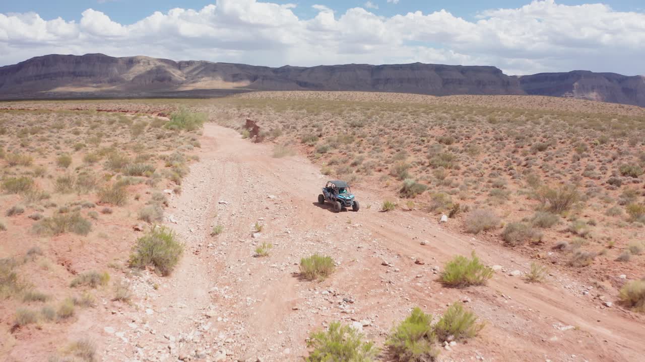 유타의 거친 사막 지형을 통해 운전하는 차량에서 멀어지는 공중 샷