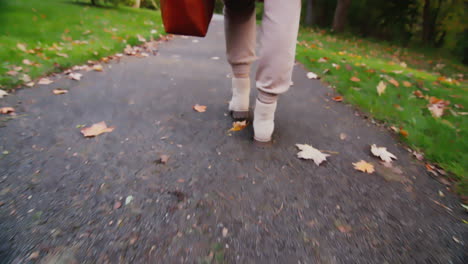 legs of a woman who walks along the path in an autumn park. follow shot