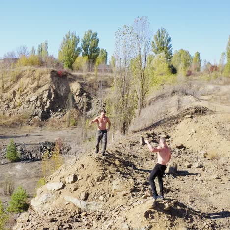 muscular sportsmen are exercising on nature background. athletic shirtless men training outdoors. sporty guys showing their strength body. aerial view.