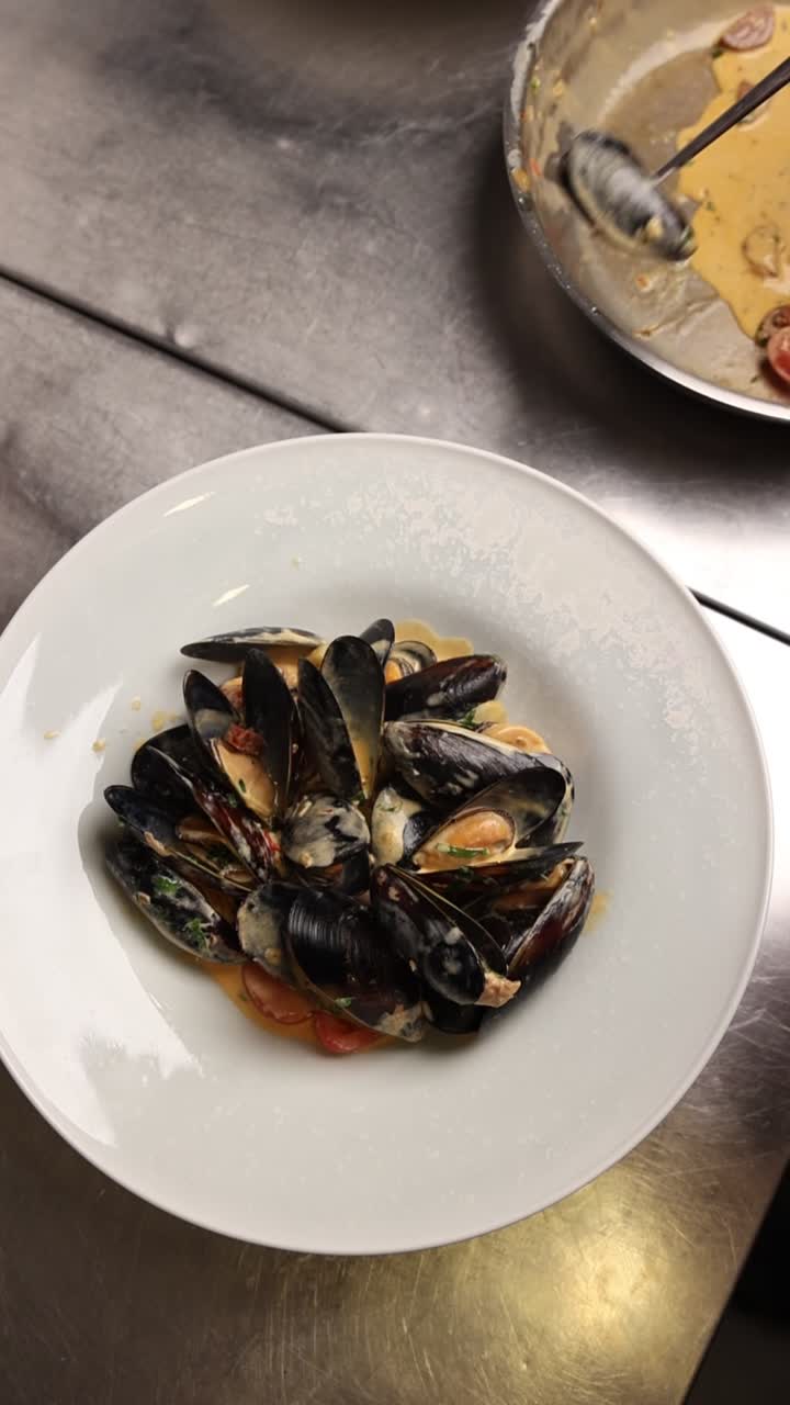 Chef Plating Fresh Mussels with Sauce in a Restaurant Kitchen