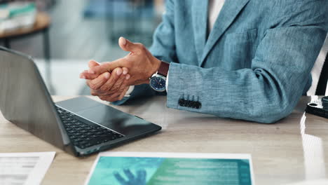 businessman in suit sitting at a desk with a laptop and papers
