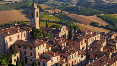 aerial video captures a scenic italian village with a historic tower, surrounded by lush hills