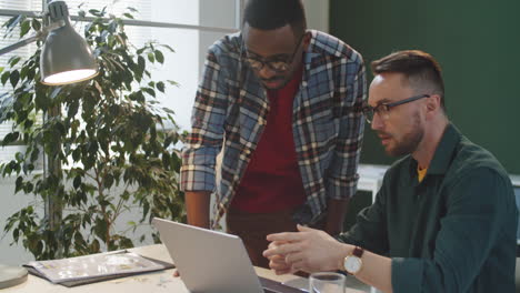 multiethnic colleagues shaking hands and discussing project on laptop