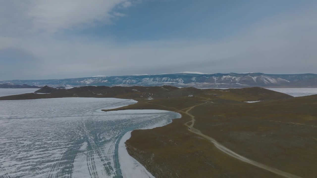 Ampio paesaggio aereo di Capo Kobylya Golova sull'isola di Olkhon, Lago Baikal, Russia, che mostra una costa frastagliata, bordi d'acqua ghiacciati, colline e strade remote