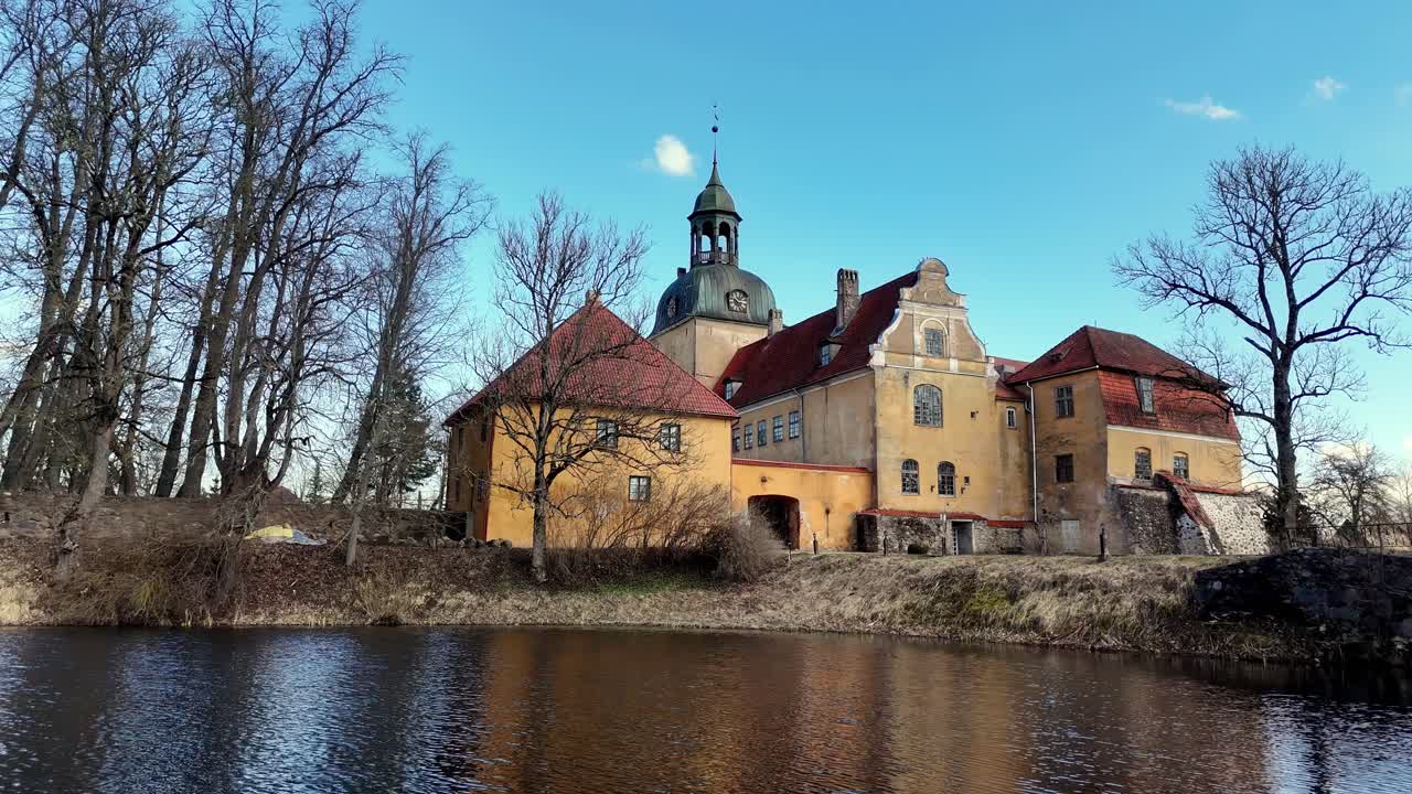 drone fly above Lielstraupe Castle Cēsis Municipality, in the Vidzeme region of Latvia clear sky daylight and lake pond water medieval fortress