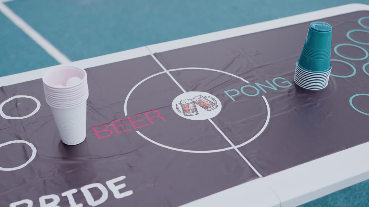 beer pong table with stacked plastic cups placed outdoors on a blue surface