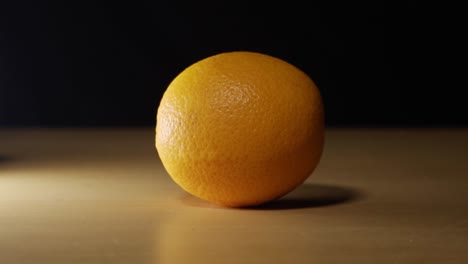 fresh orange laying on a table with black screen background