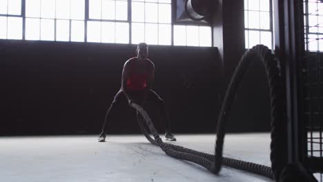 african american man exercising battling ropes in an empty urban building