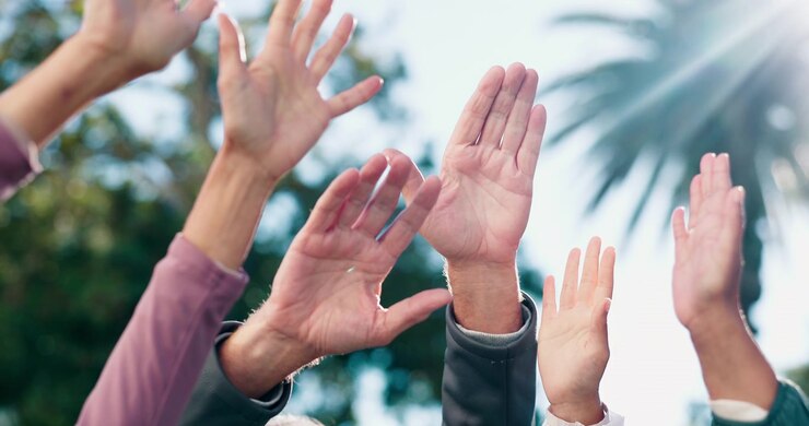 Diverse Group of People Raising Hands Together Outdoors