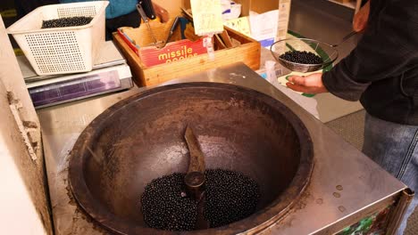 person roasting coffee beans in a large pan