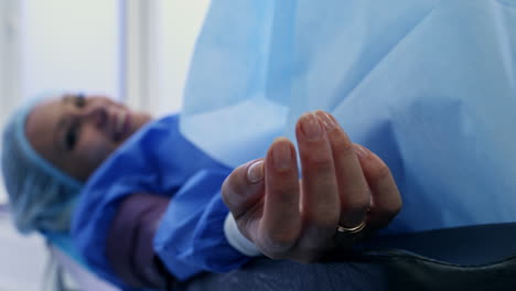 medic's hand puts a sensor on patient's finger. close up. conscious female patient smiling and talking to doctors. blurred backdrop.