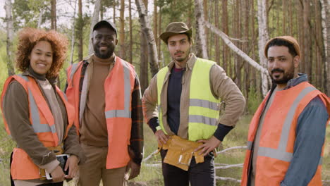 multiethnic group of ecologist activists posing and smiling at the camera in the forest