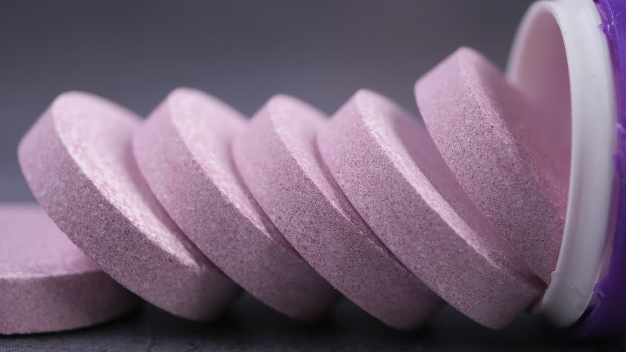Tabletas efervescentes rosas vertiéndose de un envase
