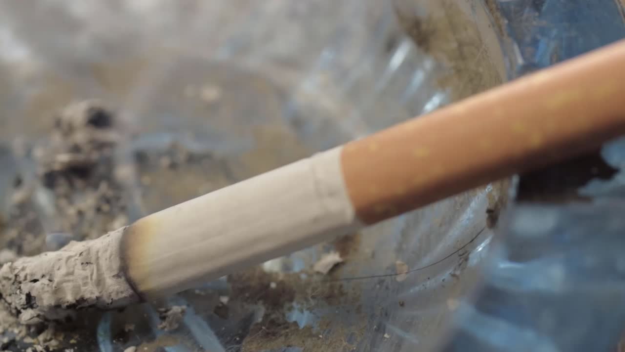 Lit cigarette smoking and burning in an ashtray