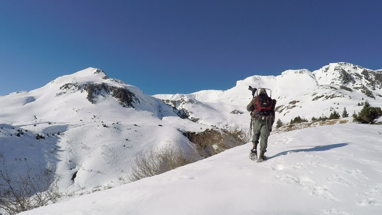 A nature and wildlife photographer snowshoes up into the snow covered mountains of Kodiak Island Alaska in preparation for a winter photoshoot