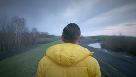 young man in yellow coat working in rural landscape in slow motion