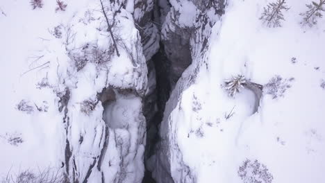 Antenne:-Tiefe-Schlucht,-Schmale-Wände-Verstecken-Im-Winter-Einen-Eisigen-Fluss-Weit-Unten