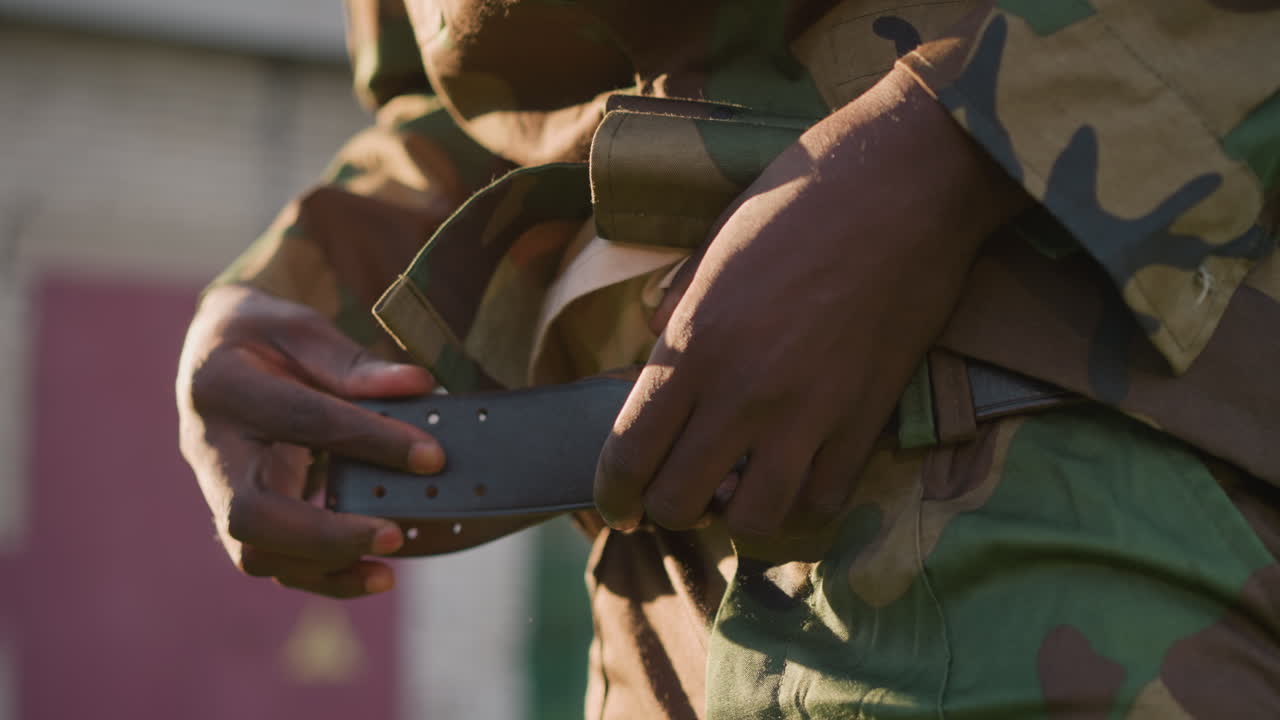 Focus On Soldier Securing His Camouflage Attire, Detailed Shot Of Soldier Fastening Belt With Leather Strap, Intimate View Of Military Personnel Preparing For Service By Adjusting His Gear