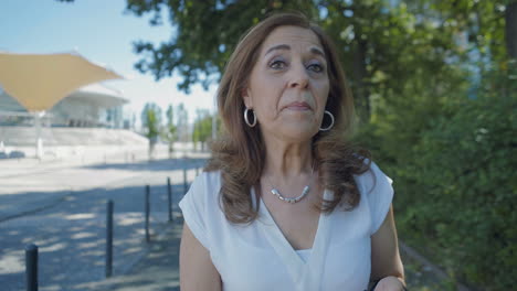 elegant woman walking outside, looking at camera, talking