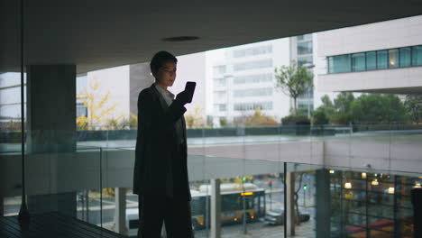 Thoughtful-businesswoman-looking-smartphone-on-dark-balcony.-Nervous-woman-walk