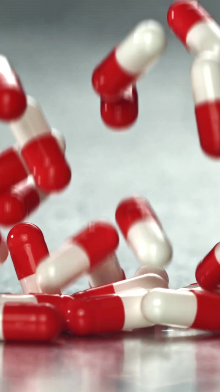 Capsule rosse e bianche che cadono al rallentatore.