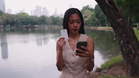 woman using mobile phone and credit card in park
