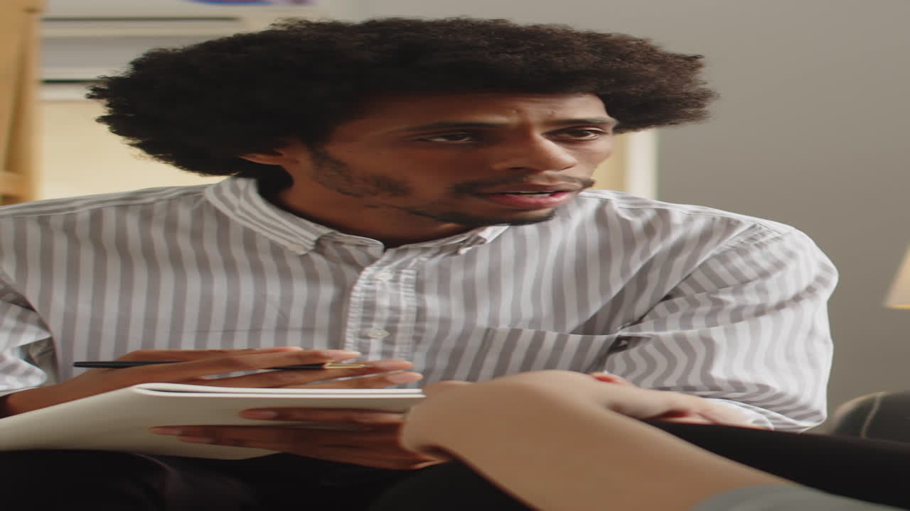 Male Psychologist Listening to Patient and Filling Form