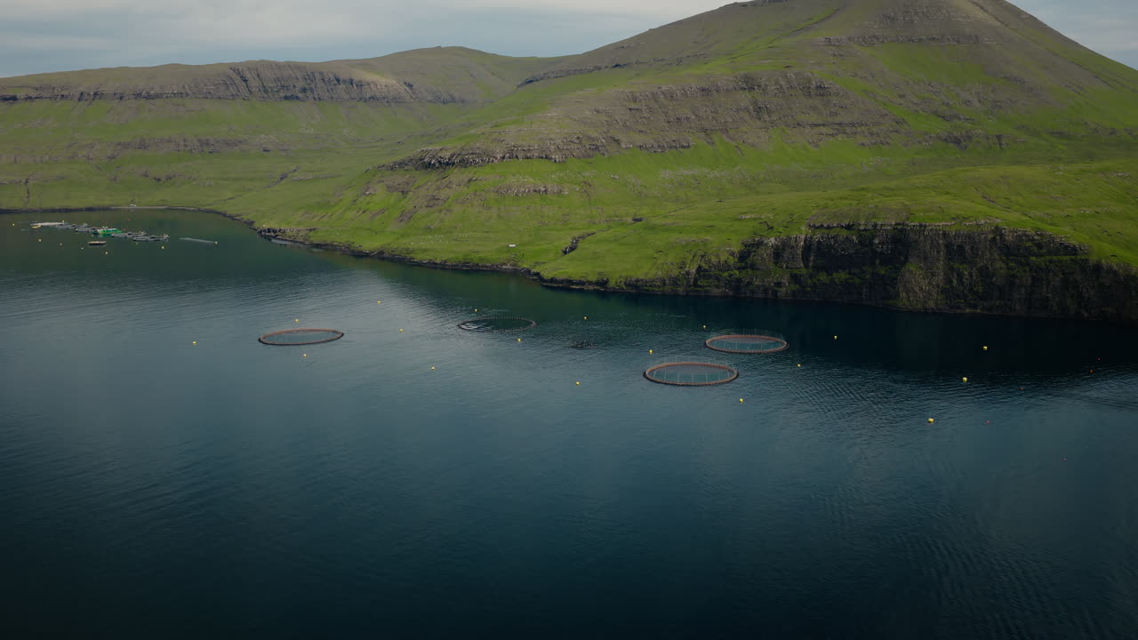 Aerial view of fish farms in a scenic fjord with green mountains