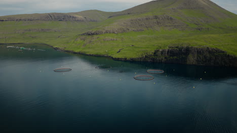 aerial view of fish farms in a scenic fjord with green mountains