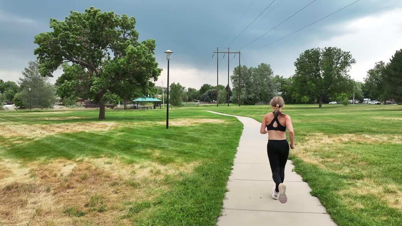 Running in wind under a stormy sky this young woman demonstrates endurance. She inspires others to live an active lifestyle