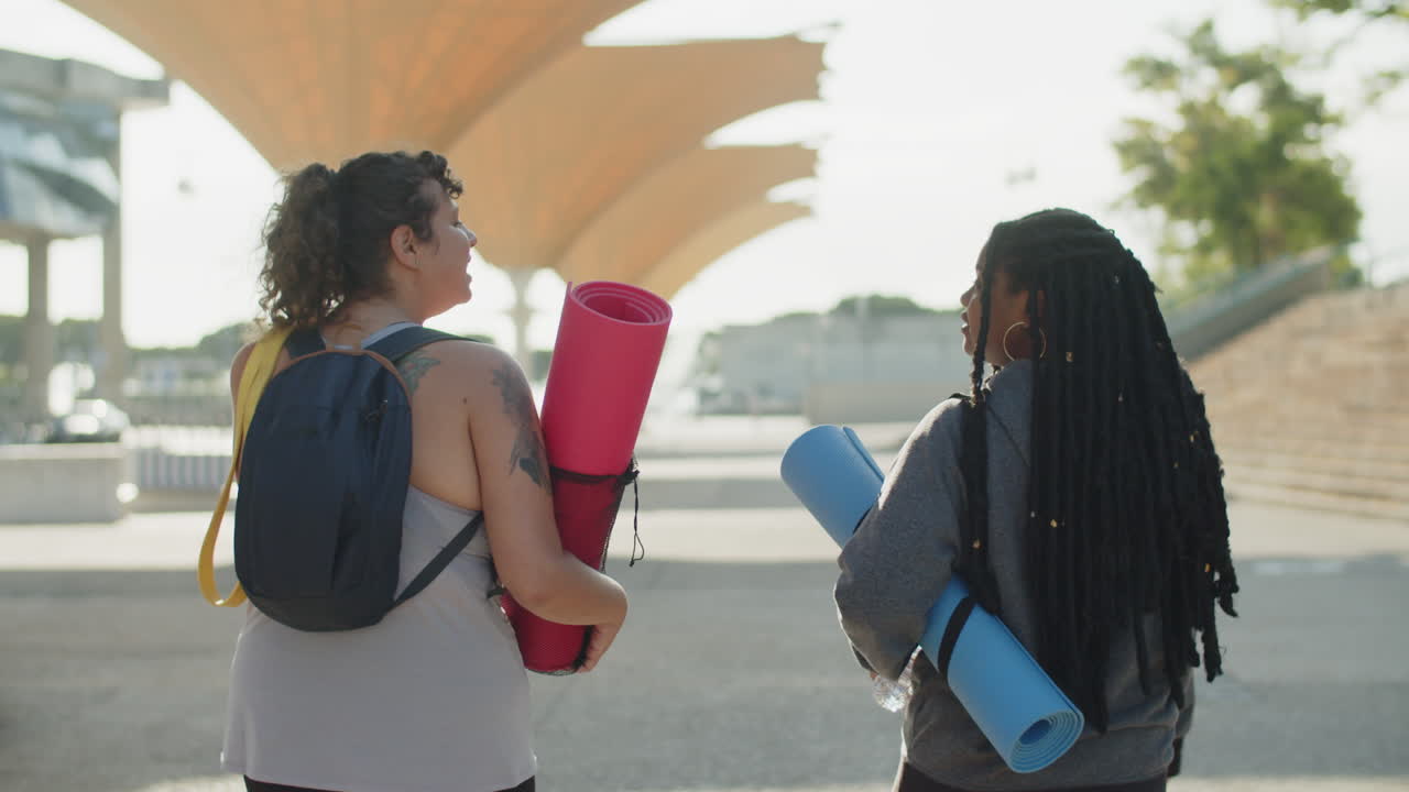 Rückansicht von korpulenten Frauen, die sich nach dem Training lebhaft unterhalten.