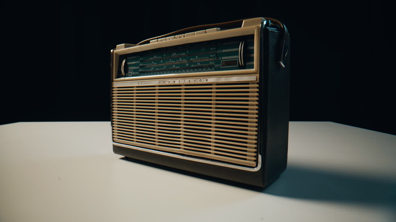 Old radio transistor standing on table in dark room closeup. Vintage FM receiver