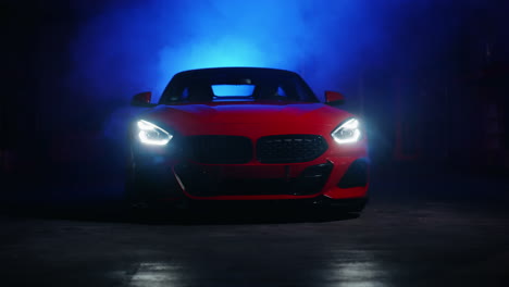 red sports car with glowing headlights in studio light setup with changing colors in fog